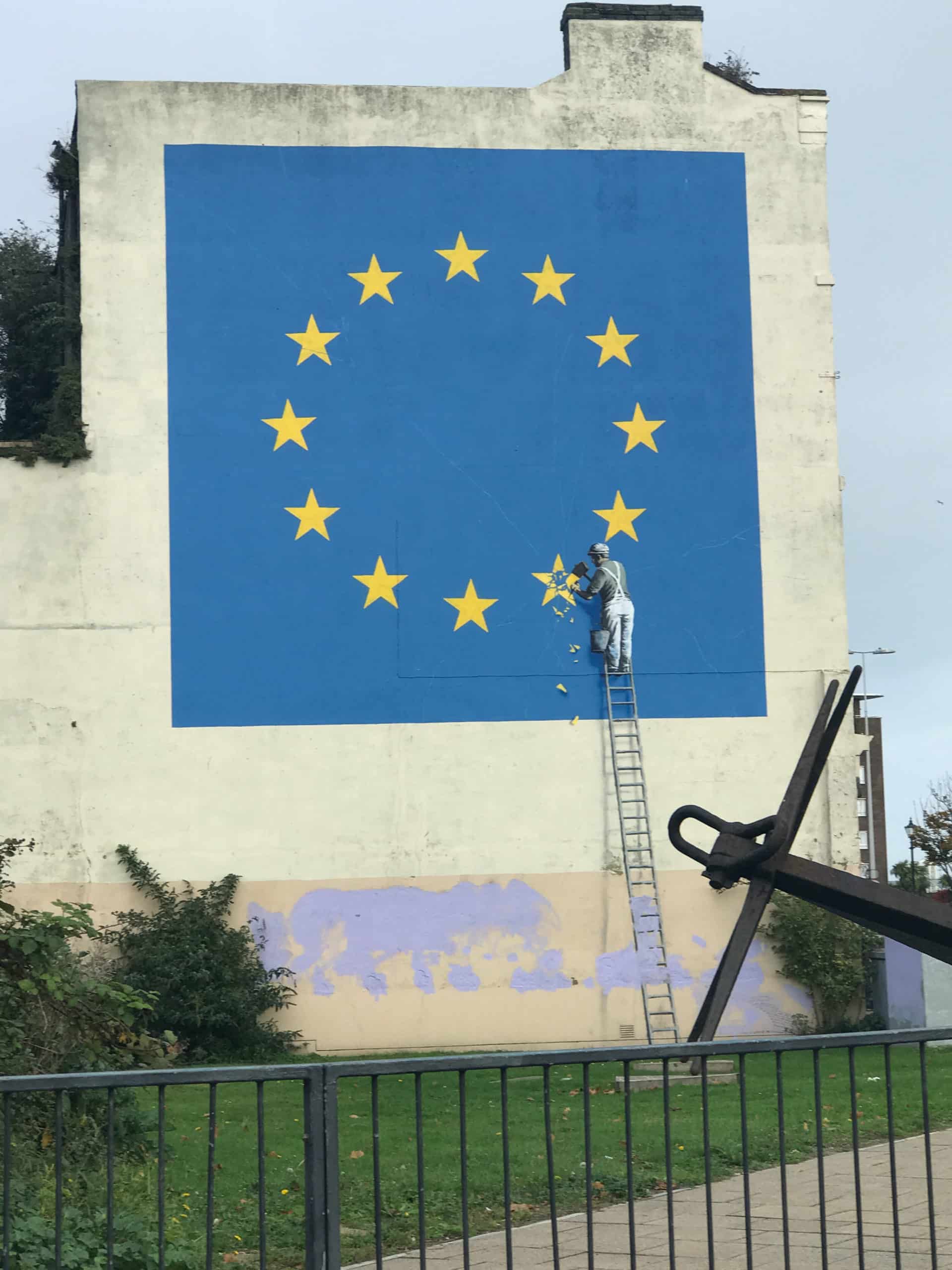 Banksy bestätigte, dass das mysteriöse Wandgemälde in Dover, auf dem eine von einem Arbeiter gemeißelte europäische Flagge zu sehen ist, von ihm stammt. Das Stück – das auf mysteriöse Weise über Nacht in einem Gebäude neben der A20 in der Nähe des Fährterminals von Dover auftauchte – zeigt die charakteristische Schablonenarbeit des Künstlers. Das Wandgemälde wurde am 20. August 2019 entfernt, höchstwahrscheinlich vom Künstler selbst.