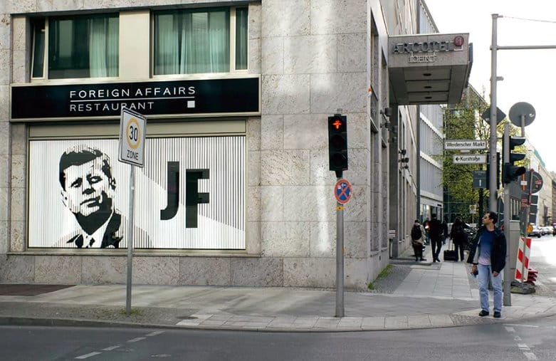 Die Klebekunst an der Fassade des JFK-Arcotel Berlin erzeugt mit seinem weißen Klebeband und den dunklen unbeklebten Fensterflächen einen interessanten optischen Effekt