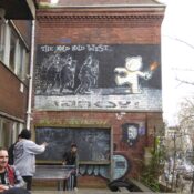 "The mild, mild west..." - Street Art Graffiti von Banksy an der Hauswand eines Café in der Stokes Croft in Bristol, England