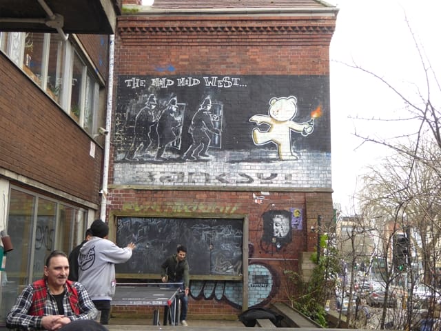 "The mild, mild west..." - Street Art Graffiti von Banksy an der Hauswand eines Café in der Stokes Croft in Bristol, England