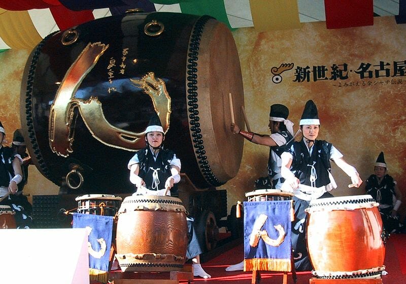 Taiko-Vorstellung nahe Nagoya-jō (Burg von Nagoya) in Japan. Die große Trommel im Hintergrund ist 240 cm lang und hat in der Mitte einen ebenso großen Durchmesser, an den Enden von 195 cm. Die Trommel wurde aus einem Stück eines 1.200 Jahre alten Baumes gefertigt und wiegt rund 3 Tonnen.