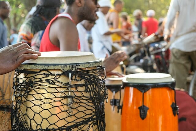 Eine Gruppe von Menschen, die Musikinstrumente wie Congas und Bongos in einem Park spielen