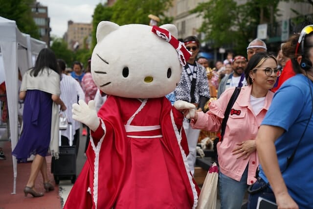 Eine Person in einem Hello Kitty-Kostüm geht eine Straße entlang