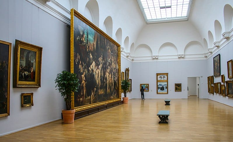 Ausstellungshalle in der Hamburger Kunsthalle. Das große Gemälde: Hans Makart, Der Einzug Kaiser Karls V. in Antwerpen, 1878. Links daneben: Ferdinand Heilbuth, Der Maler Luca Signorelli an der Leiche seines von einem Nebenbuhler erschlagenen Sohnes, 1859. Geradeaus das zweiteilige Gemälde: Giovanni Segantini, Glaubenstrost, 1896.