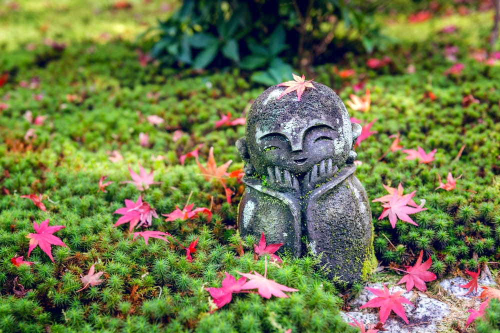 Liebenswürdige Steinskulptur inmitten von Bodendeckern