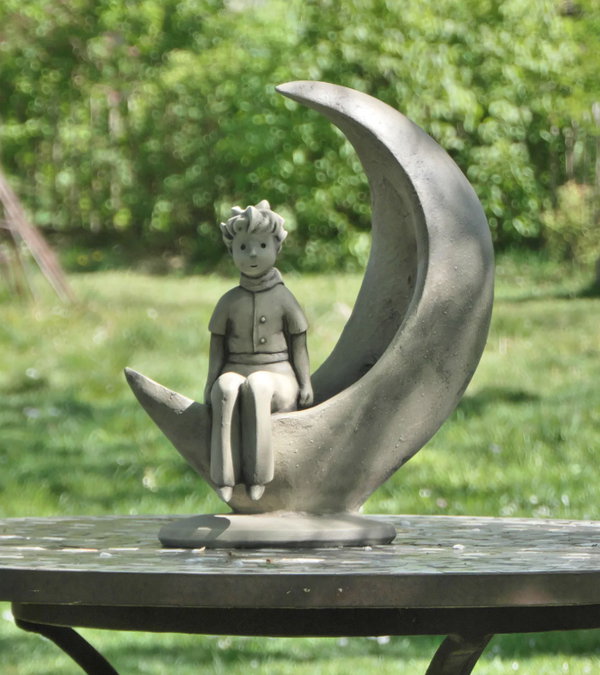 Dargestellt ist der kleine Prinz sitzend auf einer Mondsichel. Gefertigt aus Steinguss. 