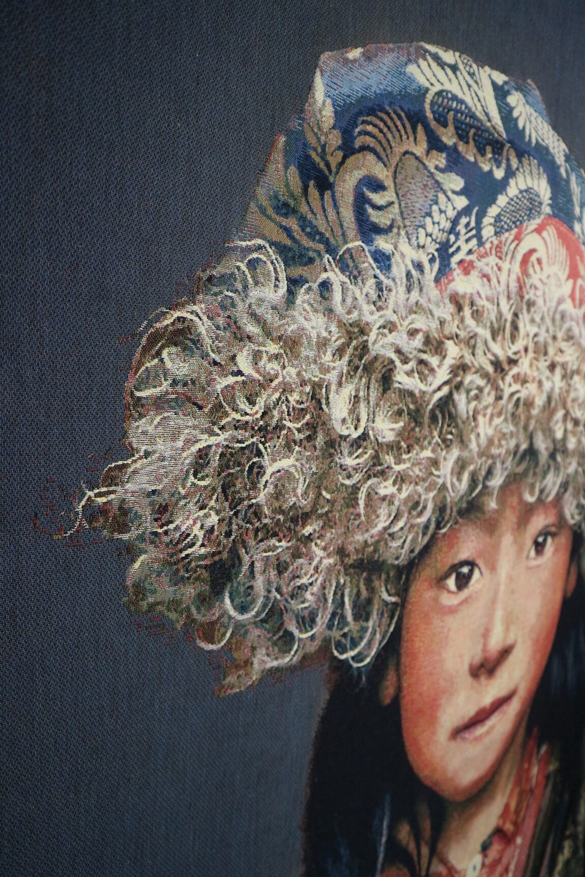 Tapiz de pared tejido a mano "Niño tibetano 2" de Alison Wright, fonoabsorbente (sobre bastidor, fondo gris) Tapiz de pared tejido a mano “Niño tibetano 2” de Alison Wright, tensado sobre un bastidor y con material fonoabsorbente (fondo gris)