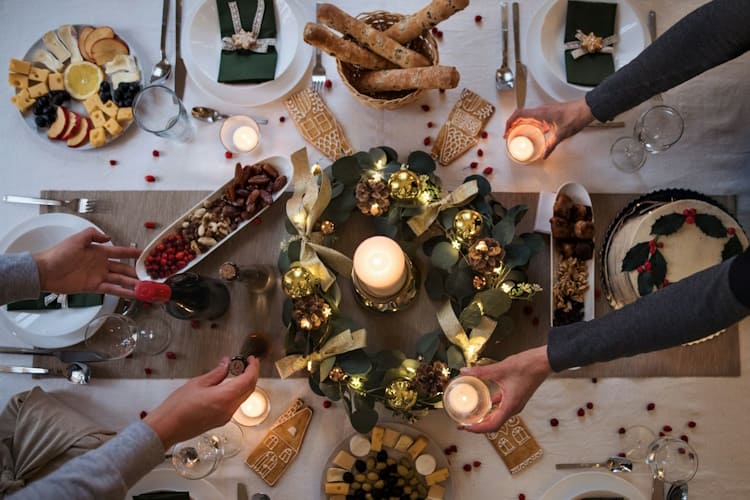 Die Weihnachtstafel als Stillleben: Was der Festtisch von der Malerei lernen kann Malerei 17. jahrhundert Festliche Tafel mit üppigem, mit Lichterketten und Goldkugeln geschmücktem grünen Kranz als strahlendem Herzstück. Zudem werden essbare Elemente wie liebevoll verzierte Lebkuchenhäuschen und verstreute rote Beeren charmant direkt in die Dekoration integriert, was für ein besonders einladendes, familiäres Ambiente sorgt.